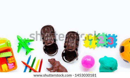 Brown leather children's sandals with colorful  toys on white background. Copy space