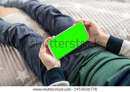 Smartphone with a green screen in hand child top view close up. Phone a for keying is holding kid. Smartphone with a hromakey in the hands of a child.