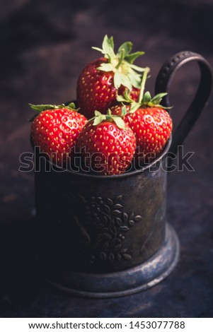 Ripe and juicy strawberries in old rustic metal cup. Selective focus. Shallow depth of field. 
