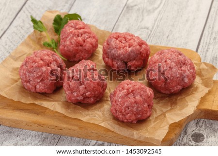 Raw meatball over wooden background ready for cooking