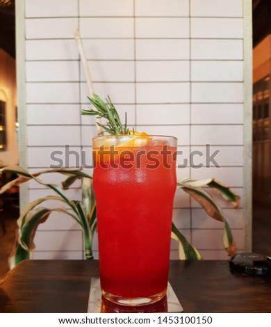 Iced fruit punch decorated with thyme on nice background in retro restaurant. The cold beverage mixed with fresh orange, strawberry & delicious fruit juices. It is  tasty & healthy. Lifestyle concept.