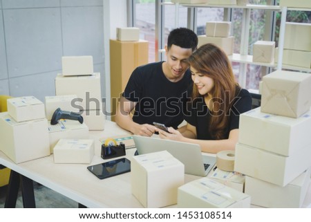 Portrait of young happy asian business couple owner of SME online using smartphone or laptop for receive order from customer at their startup home office, business seller delivery concept