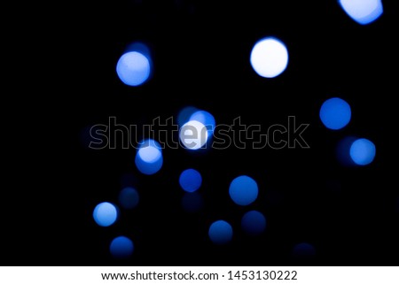 Dark abstract background with bright blue bokeh.