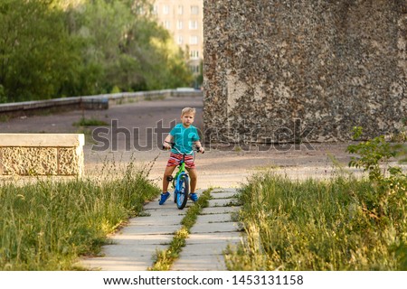 serious seven-year-old boy riding a bike in the city Park in the summer