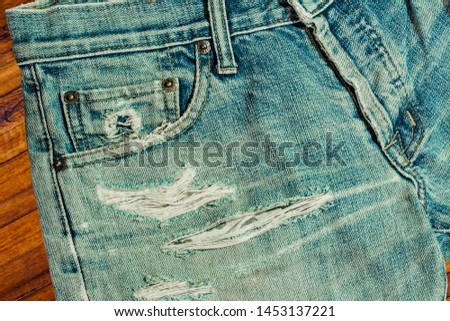 The broken jeans are placed on a wooden table.