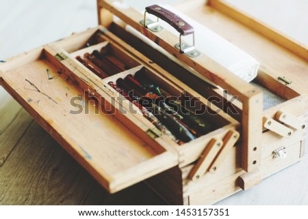 Wooden folding suitcase artist with brushes, paint and canvas. Background of a wooden floor