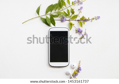 mobile phone for business work ,earphone with purple flowers arrangement flat lay style on background white at office desk 