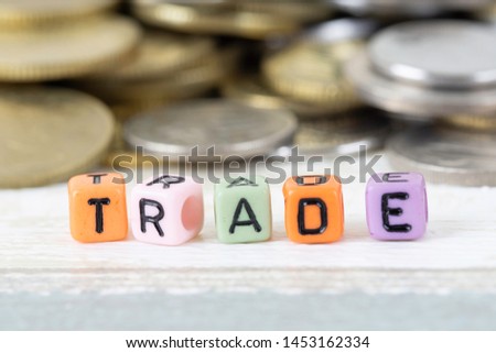 Selective focus. word "Trade" combination of colourful alphabet square beads with coins over vintage background