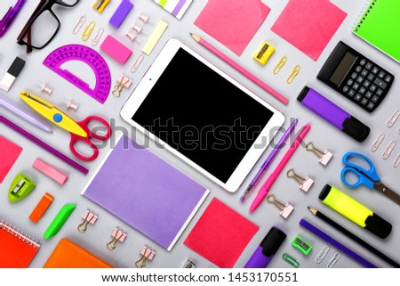 Modern tablet computer with stationery on grey background