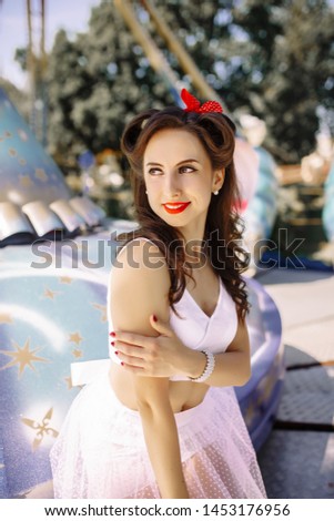 beautiful brunette girl in an amusement park in retro pin-up style in a fabulous atmosphere in pink blue and purple