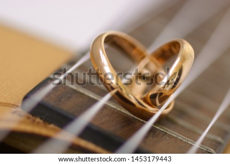 Wedding ring in a heart shape laying on ukulele guitar strings.