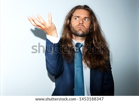 Man with very long curly hair and blue eyes in a blue suit  on a blue and white background