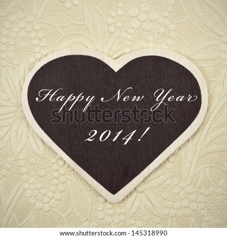 happy new year 2014 written in a heart-shaped blackboard on a vintage background, with a retro effect