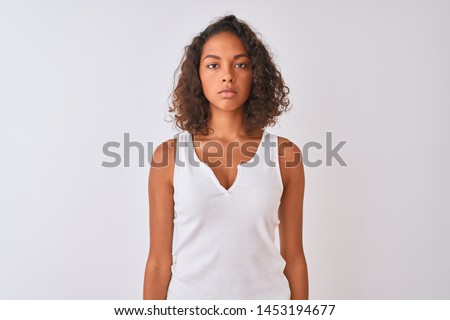 Young brazilian woman wearing casual t-shirt standing over isolated white background with serious expression on face. Simple and natural looking at the camera. Royalty-Free Stock Photo #1453194677