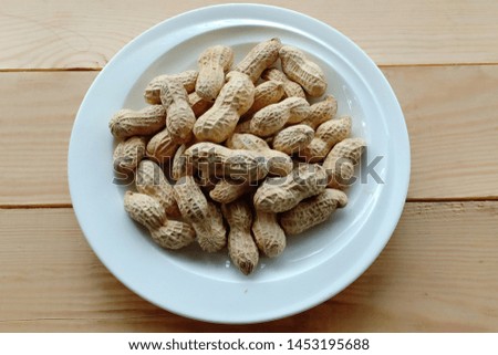 salted peanuts on white dish on brown wooden table background