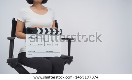 Woman is sitting on the chair and hands is holding Clapperboard or movie slate. it use in video production ,film, cinema industry on white background.