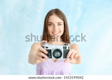 Young female photographer on color background