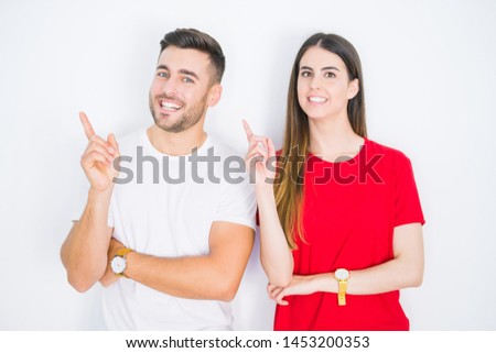 Young beautiful couple together over white isolated background with a big smile on face, pointing with hand and finger to the side looking at the camera.