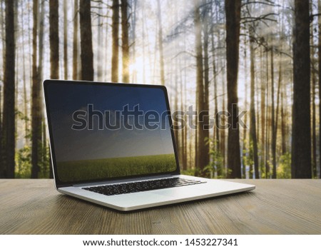 pc on wooden table, sunset forest background