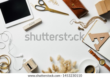 top view of smartphone, notepad, case, earphones, plants, office supplies and coffee with jewelry on white surface
