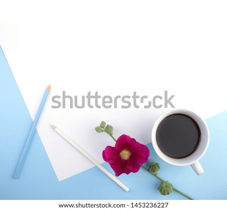 
Female desktop composition with a blank sheet of clipboard, pencil, cup of coffee, flowers on a blue background. A girl in the workplace, flowers for good morning. Top view, flat lay, close-up, copy 