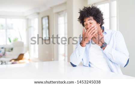 African American man at home bored yawning tired covering mouth with hand. Restless and sleepiness.