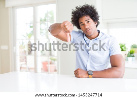 African American business man looking unhappy and angry showing rejection and negative with thumbs down gesture. Bad expression.