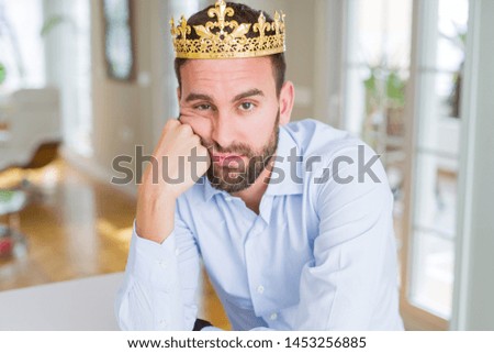 Handsome business man wearing golden crown as a king or prince thinking looking tired and bored with depression problems with crossed arms.