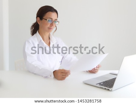 Female doctor evaluating her patient's results seriously  by sitting on a desk in her office isolated on white