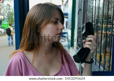 The girl holds a payphone tube. Close-up.   The concept Access before telephone communication. An girl call from the public telephone. Royalty-Free Stock Photo #1453295624
