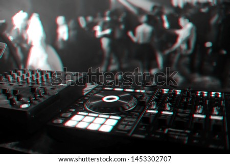 control DJ for mixing music with blurred people dancing at a party in a nightclub. Black and white photo with glitch effect and small grain