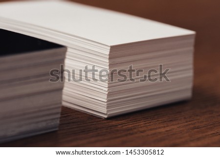 selective focus of stacked white and black empty business cards on brown wooden surface