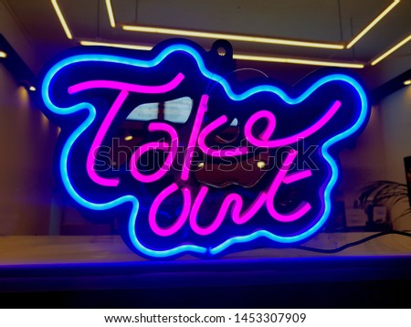 A takeaway neon sign hanging in a cafe.