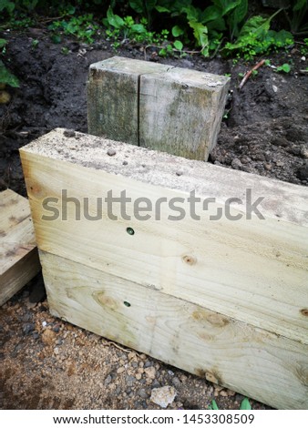 A garden being landscaped using large wooden sleepers as borders for flower and plant beds and edges of a lawn