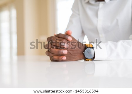 Close up of crossed hands of african man over table