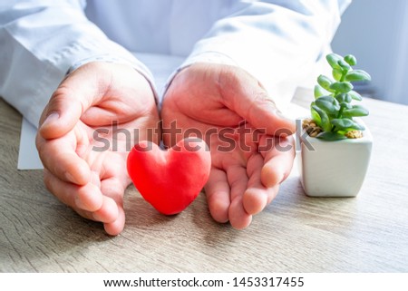 Protection, treatment, prevention and patronage health of heart and cardiovascular system against diseases and pathologies concept photo. Doctor surrounded heart shape with his hands on his desk Royalty-Free Stock Photo #1453317455