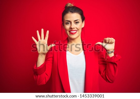 Young beautiful business woman standing over red isolated background showing and pointing up with fingers number six while smiling confident and happy.