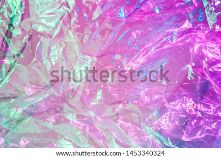 Holographic background in the style of the 80-90s. Real texture of cellophane film in bright acid colors. Royalty-Free Stock Photo #1453340324