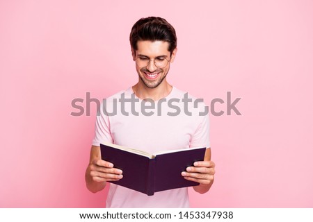 Portrait of his he nice attractive content confident diligent focused cheerful cheery intelligent guy reading book library isolated over pink pastel background