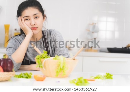 Young woman or housewife is bored of cooking, which consists of a variety of fruits and vegetables for the family. Royalty-Free Stock Photo #1453361927