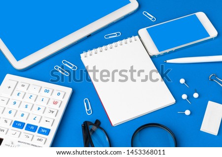 Flat lay, top view of blue office table desk. Workspace with blank note book,  office supplies 