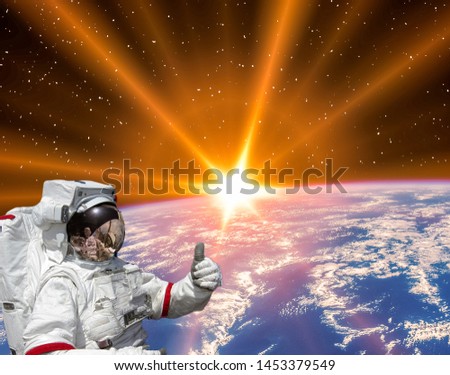 Planet earth and fascinating sunrise. Astronaut give thumbs up. The elements of this image furnished by NASA.
