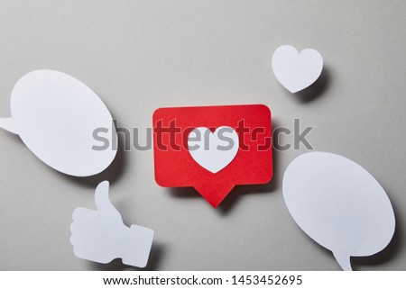 red like card, speech bubbles, thumbs up and small paper heart on white surface