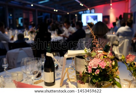 Evening event with flowers and wine bottles on the tables Royalty-Free Stock Photo #1453459622