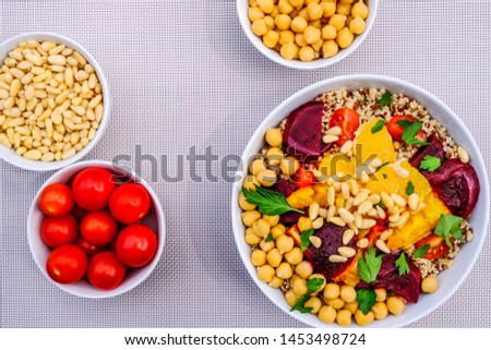 Vegetarian Or Vegan Bulgur Wheat And Quinoa Grains Lunch Bowl, With Orange Segments, Chickpeas, Beetroot And Tomatoes, On A Purple Background