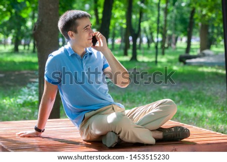 attractive adult man sitting alone on bench in park. Portrait