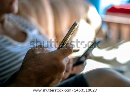 Close up of two people using mobile phone. Man and women typing an sms message to their friends. Selective focus picture of unrecognized caucasian couple using smartphones at home.