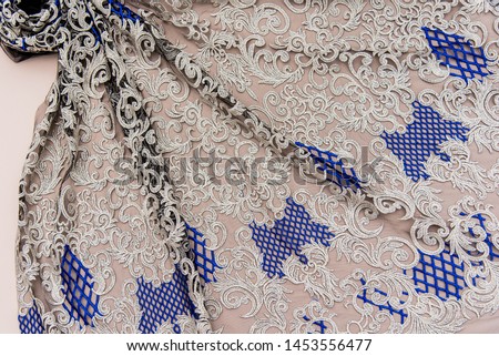 Texture lace fabric. lace on white background studio. thin fabric made of yarn or thread. a background image of ivory-colored lace cloth. Silver or gold and blue lace on beige background.