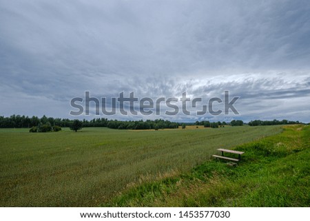 storm rain clouds forming over the countryside fields in green summer evening