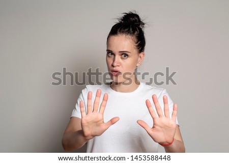 Calm, confident young woman put his palms forward as protection, calming someone down and looking at the camera. Isolated on white background. Close-up. Royalty-Free Stock Photo #1453588448